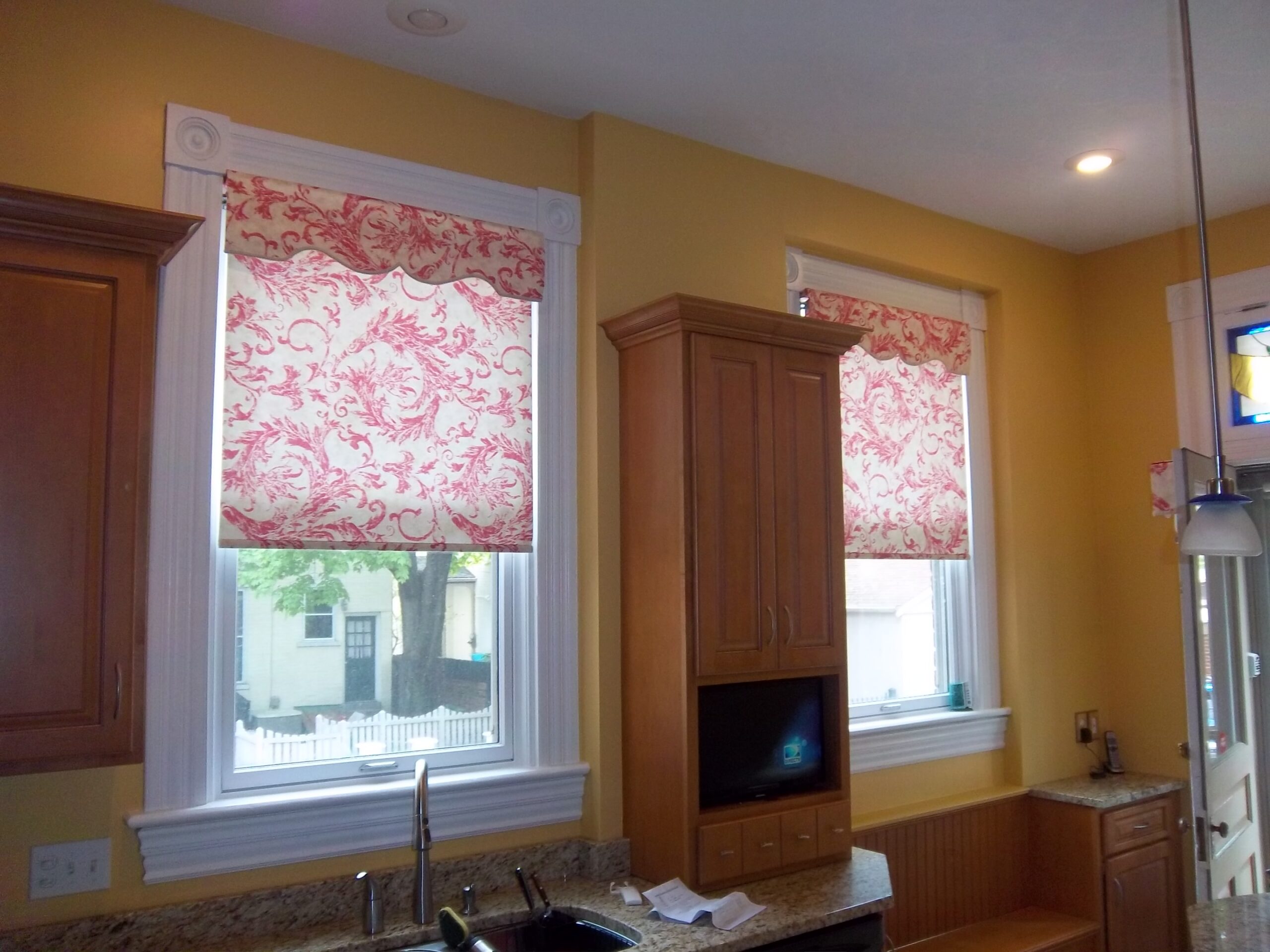 A kitchen with two windows and a microwave.